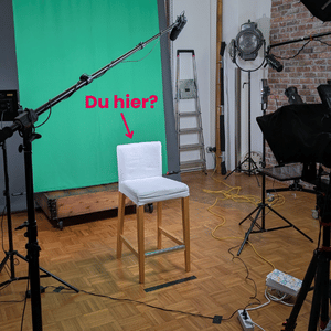 Ein weißer Stuhl steht vor einem Greenscreen in einem Tonaufnahmestudio.